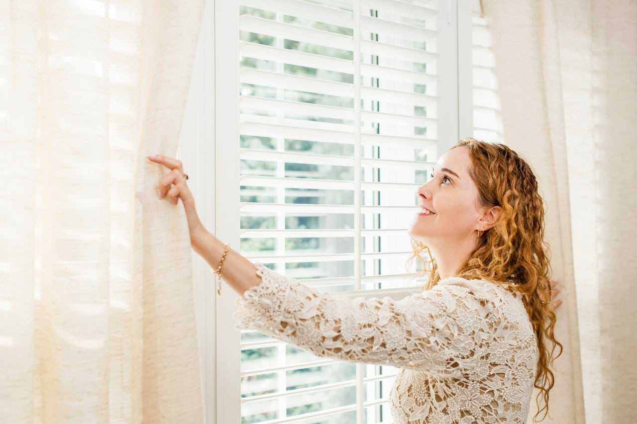 woman looking over a wood custom blinds Blind Guy of Tri-Cities